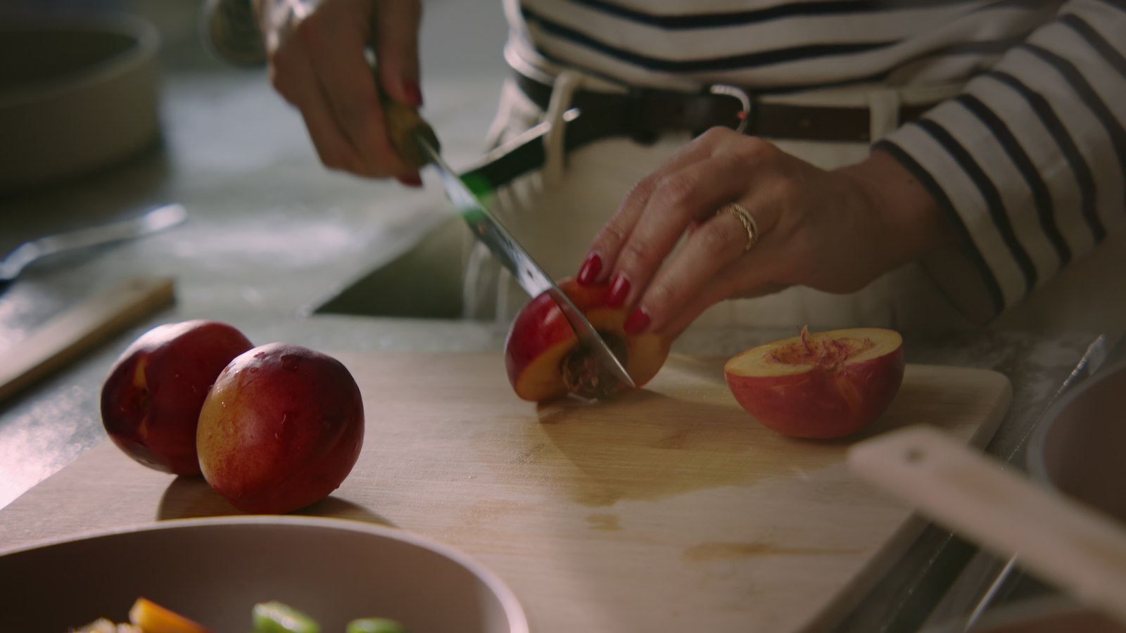 Hands slicing an apple on a wooden cutting board