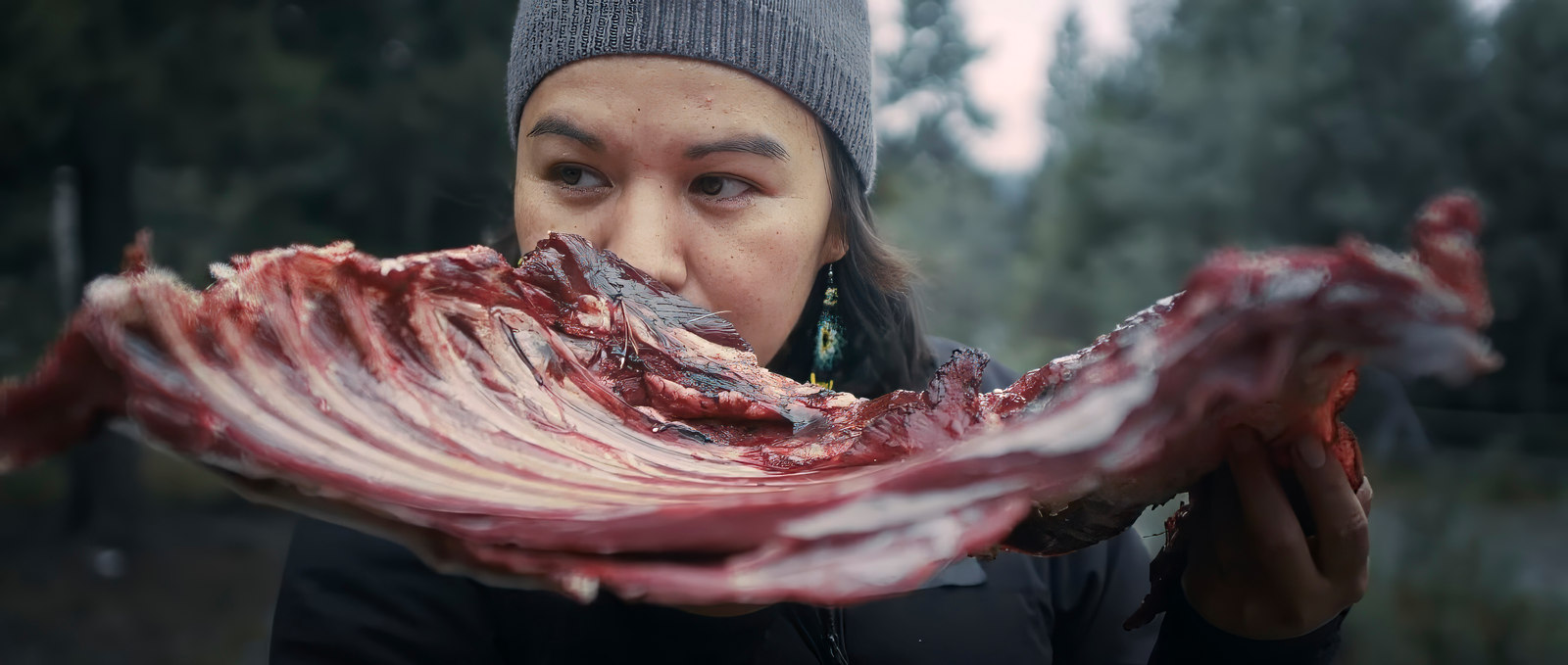 A chef holding a prepared rack of ribs outdoors