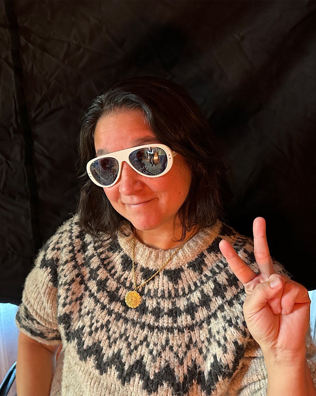 A candid portrait wearing Wayne-style white sunglasses and making a peace sign