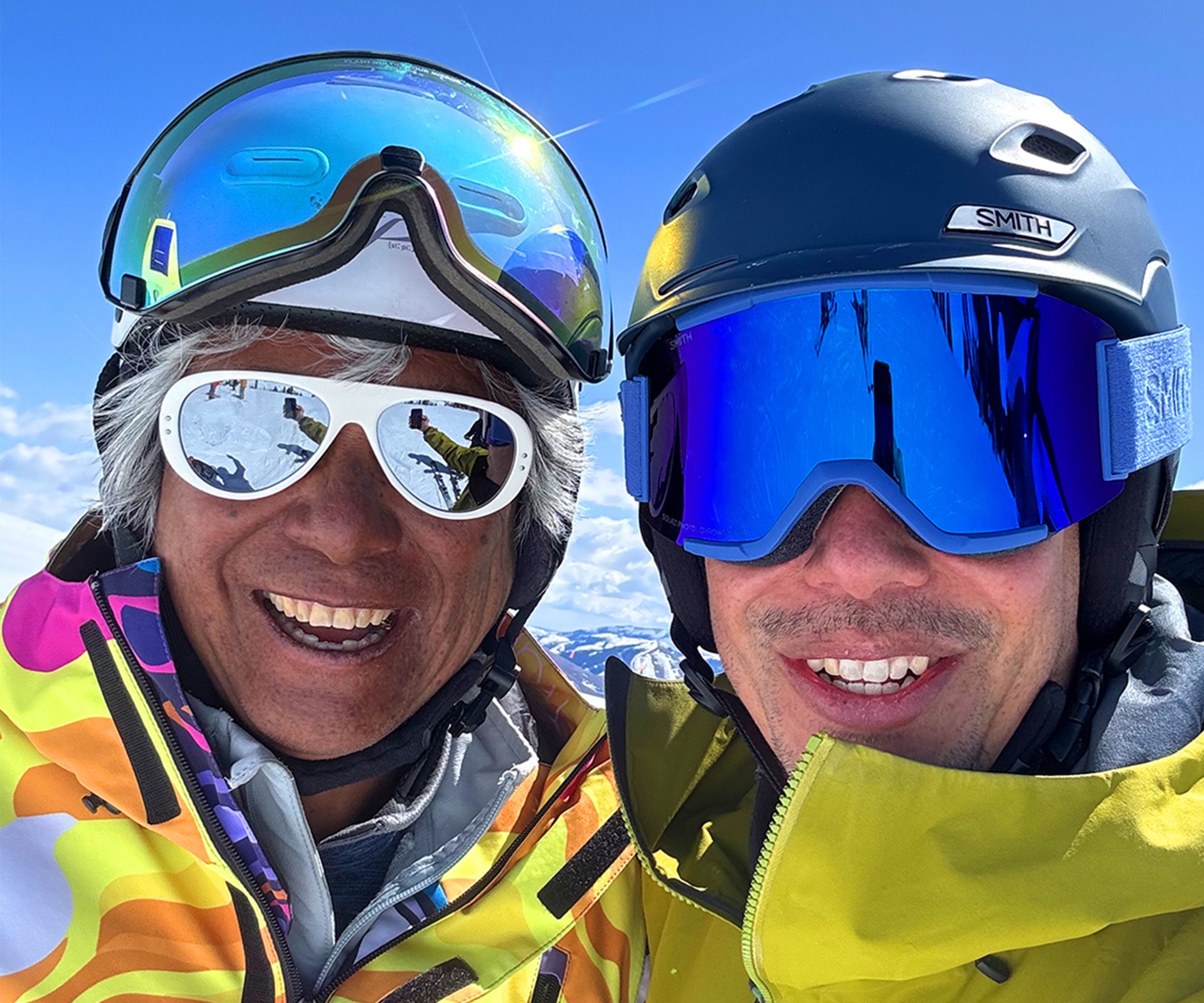 Wayne and a companion on the mountain in ski helmets and goggles